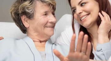 A younger woman is smiling, with her arm around an older woman