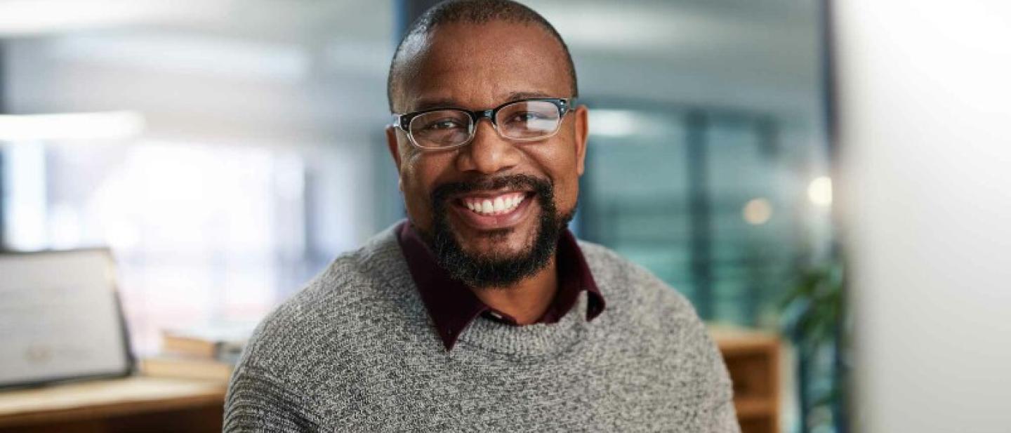 A picture of a smiling man with a beard and glasses
