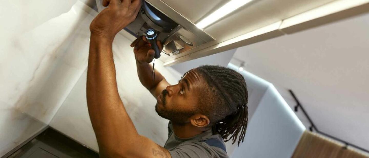 A man is fixing a ceiling with a drill
