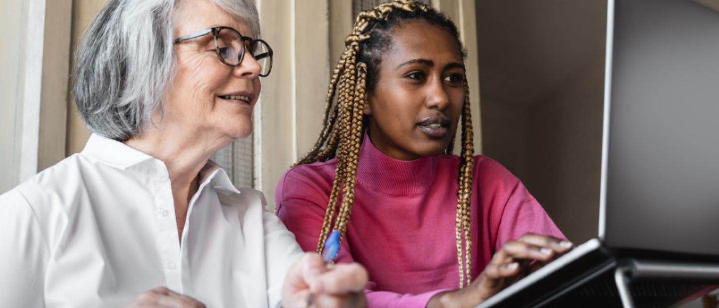 Two women work together on a laptop